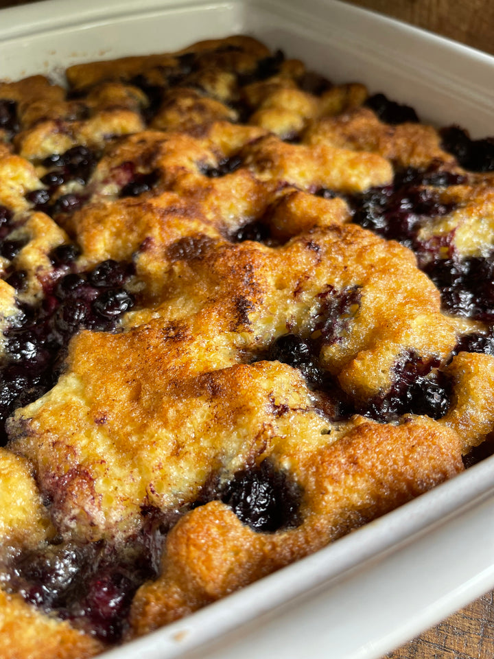 The Best Blueberry Coffee Cake in a white pan sitting on a wood table
